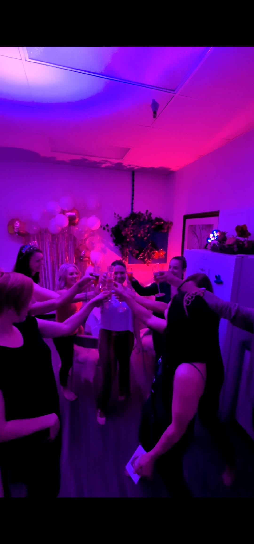 Party guests raising glasses in a toast circle